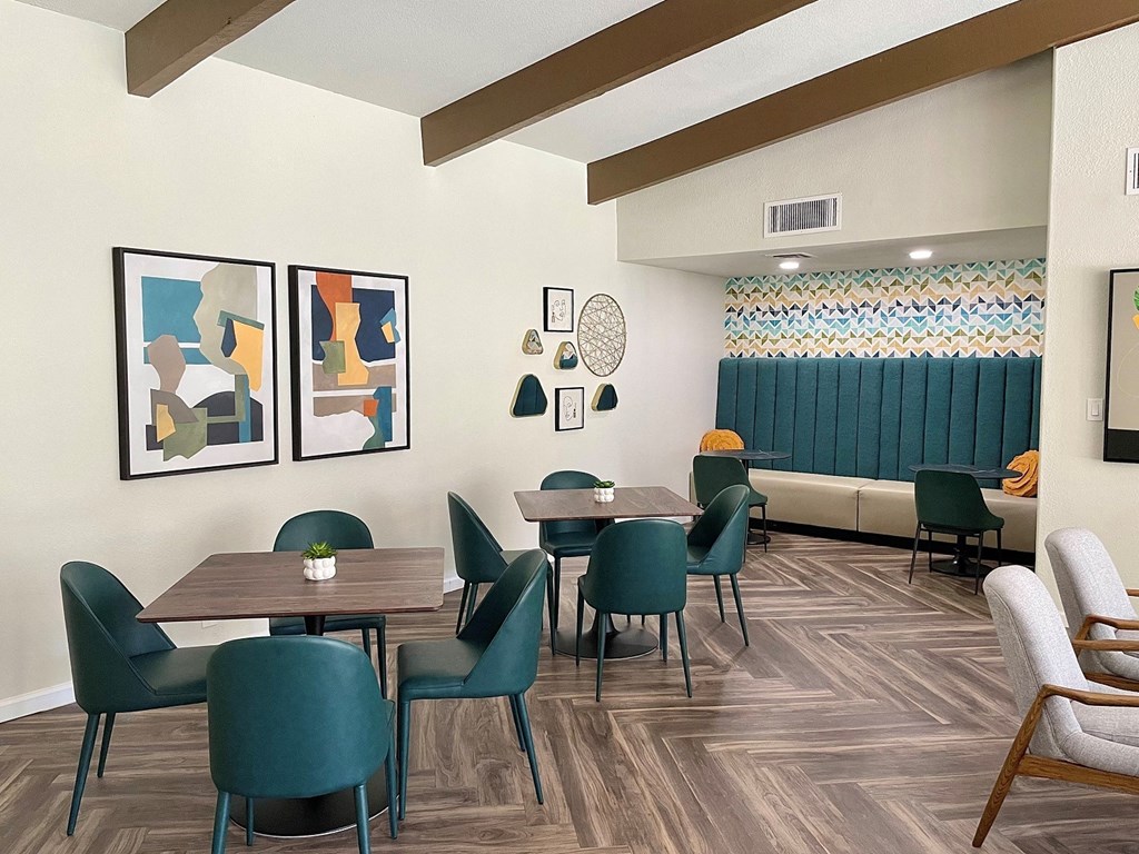 a dining area with tables and chairs and paintings on the wall