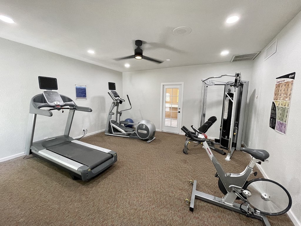 a home gym with exercise equipment and a ceiling fan