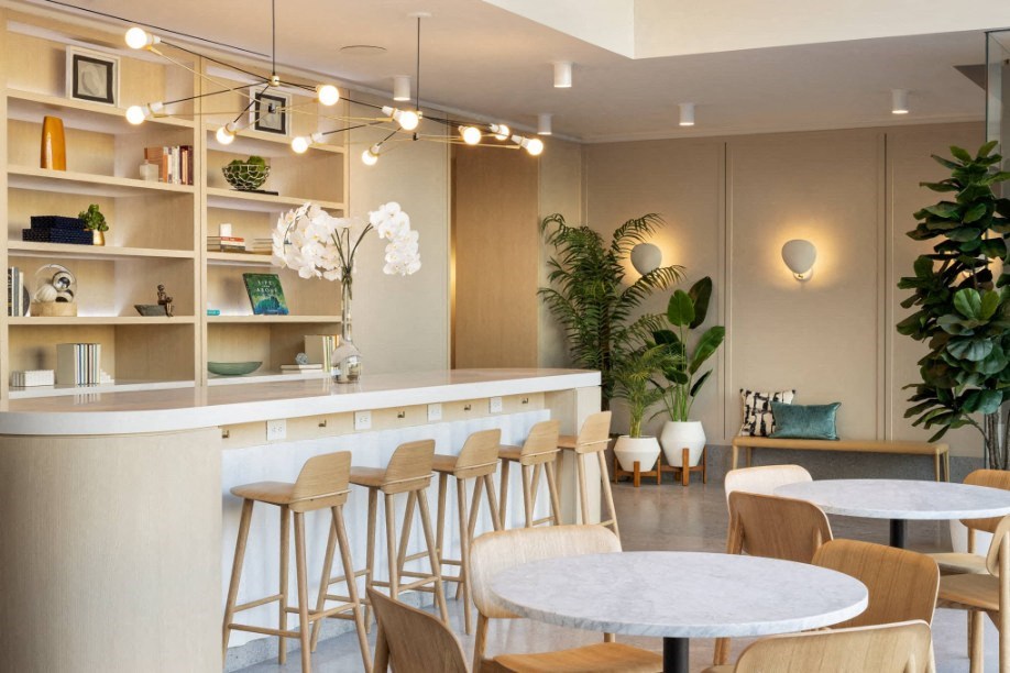 a restaurant with white tables and chairs and a bar with stools