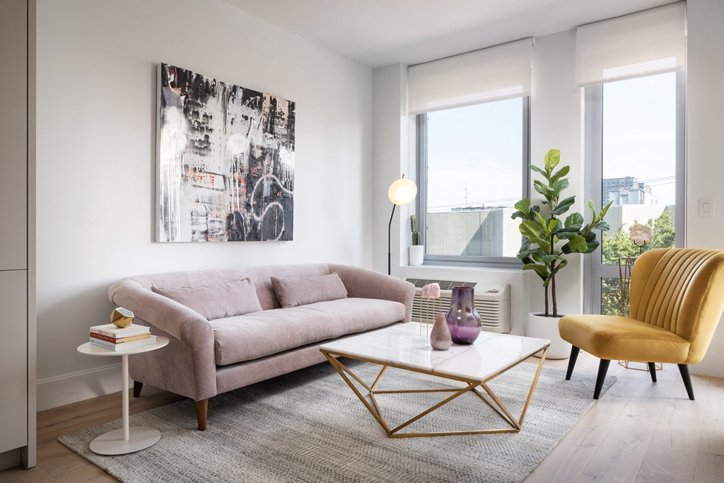 a living room with a pink couch and a table    and a window