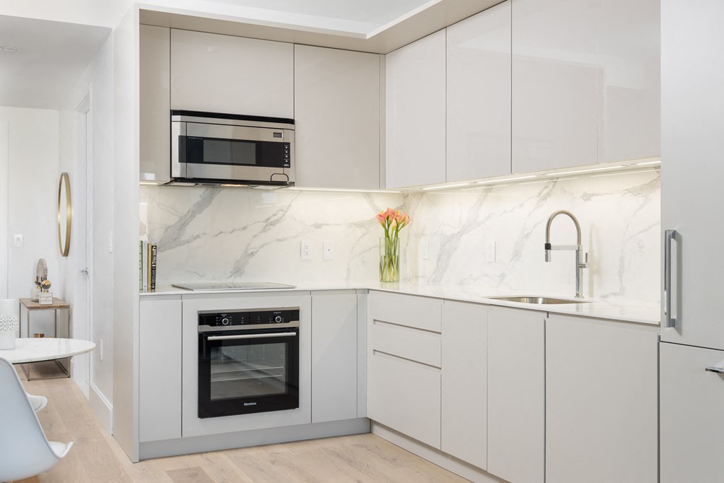 a kitchen with white cabinets and a marble counter top