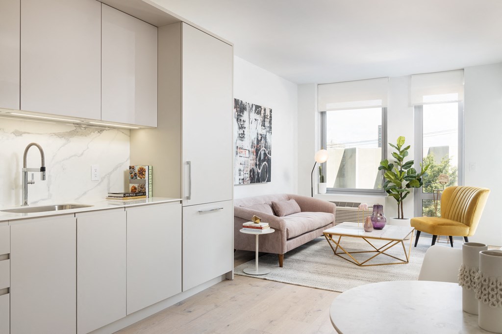 a kitchen and living room with white cabinets and a pink couch