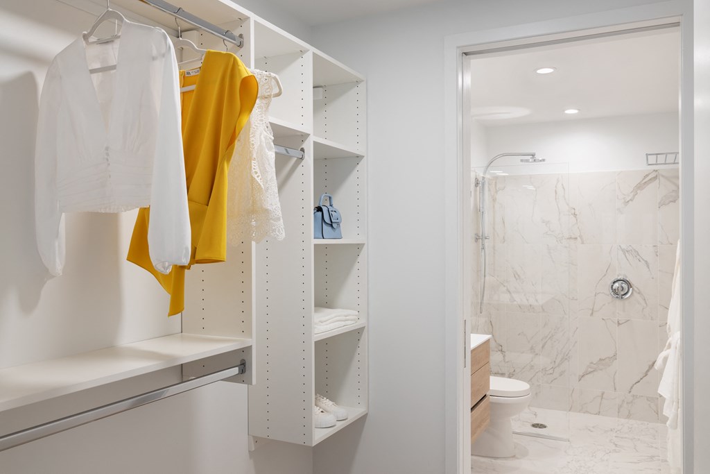 a small bathroom with a shower and a closet with white and yellow towels