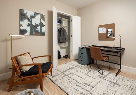 a bedroom with a desk and a chair and a door to a closet