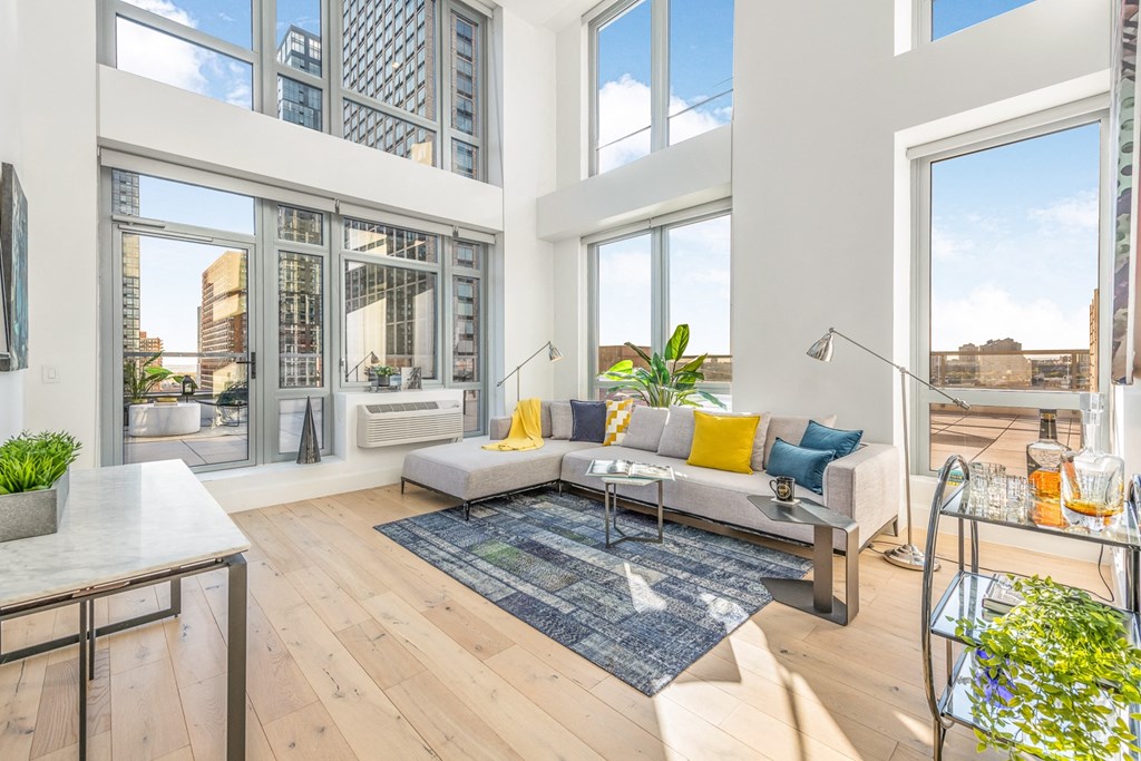 a living room with large windows and a couch and a rug