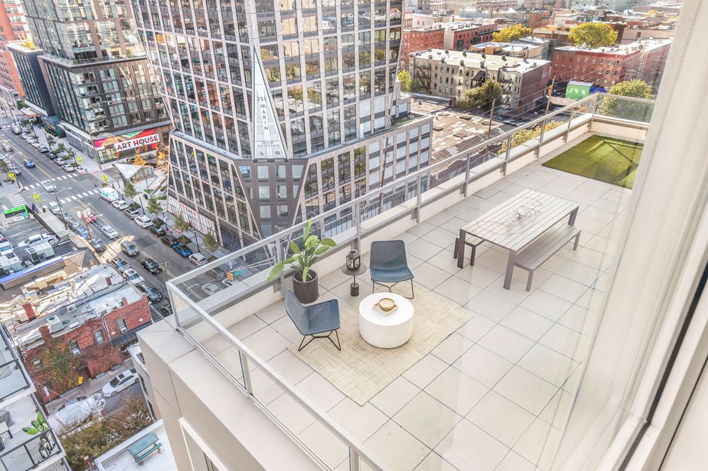 a balcony with a view of a city and a table and chairs