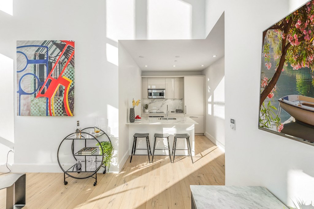 a living area with a kitchen and a table with three stools