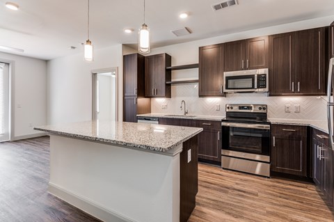 A modern kitchen with dark wood cabinets and stainless steel appliances.