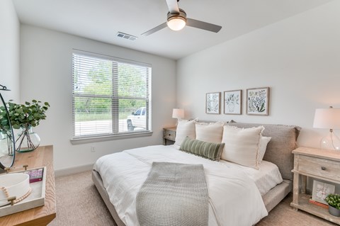 A well-lit bedroom with a large bed and a ceiling fan.