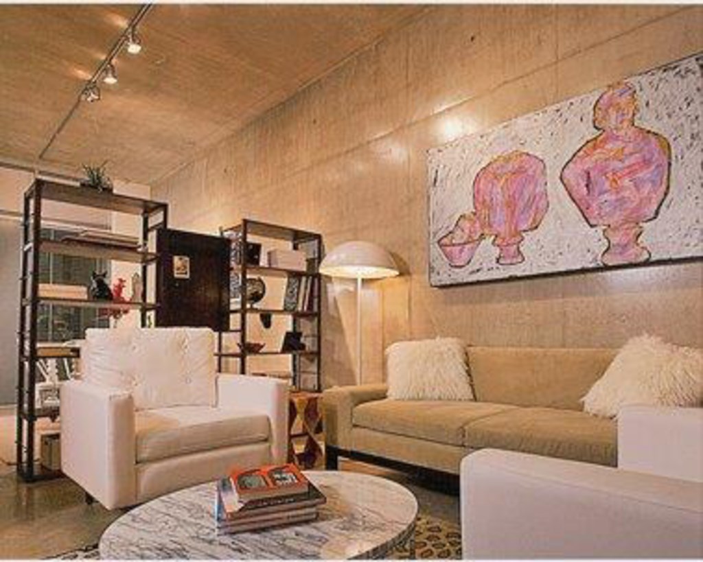 A living room with a white couch, a white chair, and a coffee table with a book on it.