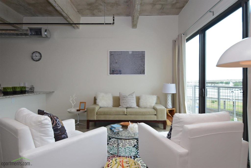 A living room with a couch, chairs, and a rug.