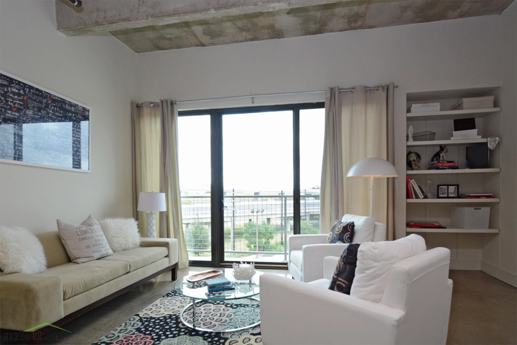 A living room with a couch, chair, and a table with a lamp on it.