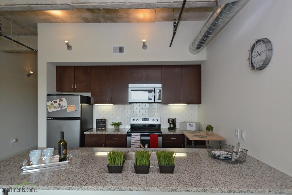A kitchen with a granite countertop and a clock on the wall.