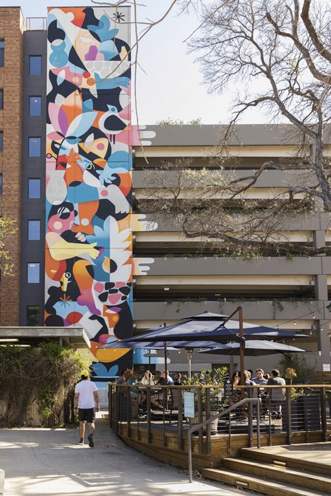 Outdoor courtyard with colorful mural and dining area at THE'68 Apartments, Texas