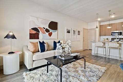 A modern living room with a white couch, a coffee table, and a large abstract painting on the wall.