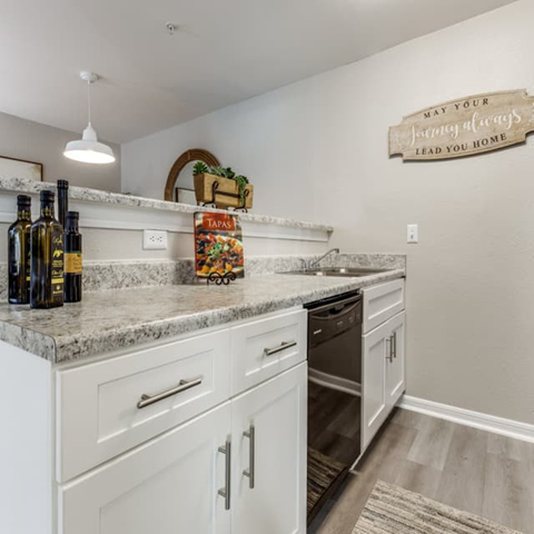 A kitchen with white cabinets and a marble countertop.