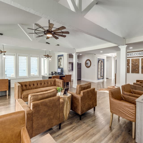 A living room with brown chairs and a ceiling fan.