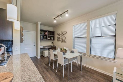 A dining room with a table set for two and a kitchen area in the background.
