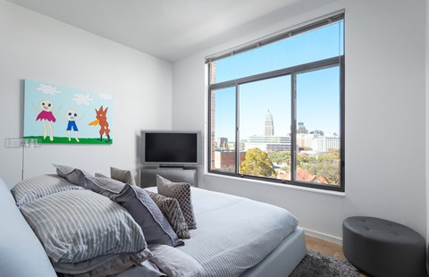 Bedroom with large window and city skyline views at THE'68 Apartments, San Antonio, TX