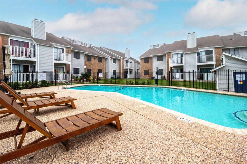a swimming pool with two wooden benches next to an apartment building at Northchase, Austin, TX, 78753