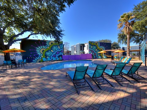 Pool area with lounge chairs and artistic wall at Azure Apartments, Austin, 78752