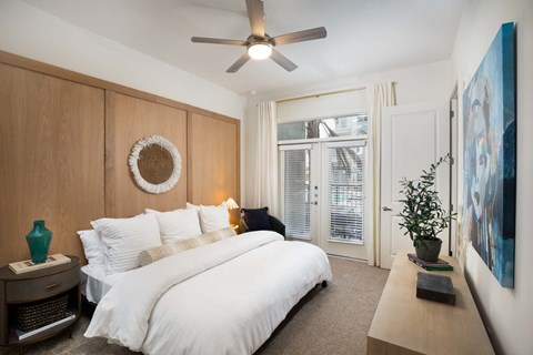 A bedroom with a large bed and a ceiling fan.