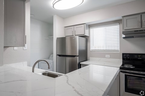 A kitchen with a white counter top and stainless steel appliances.