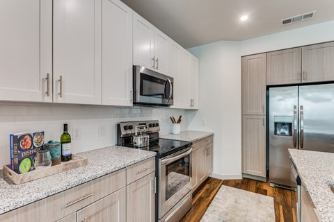 A kitchen with a microwave on the counter and a refrigerator in the background.