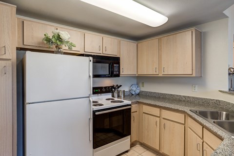 A kitchen with a white refrigerator and wooden cabinets.