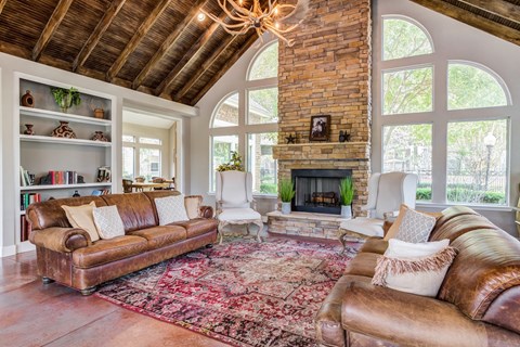 A living room with a brown leather couch and a fireplace.