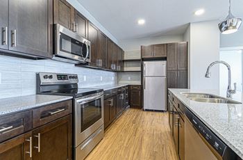 a kitchen with wooden cabinets and stainless steel appliances at The Fitzroy San Marcos, San Marcos, TX