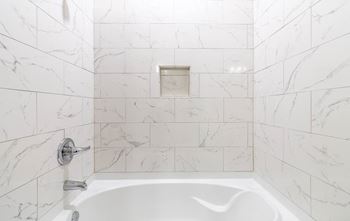 a white tiled bathroom with a tub and a sink at The Fitzroy San Marcos, San Marcos, Texas