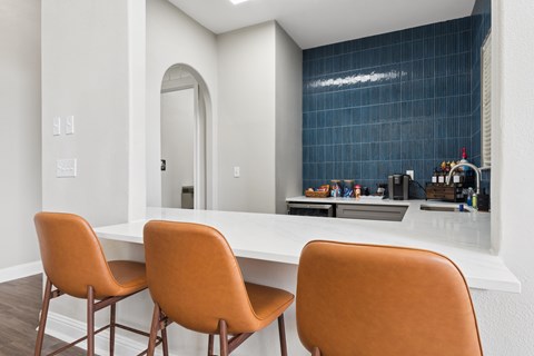 Three orange chairs are placed around a white table.