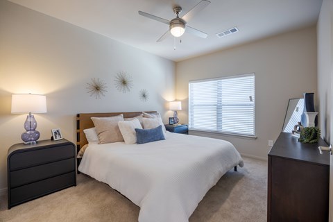 A bedroom with a bed, dresser, and ceiling fan.