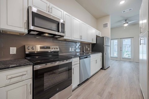 A modern kitchen with white cabinets and stainless steel appliances.
