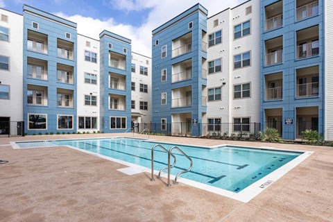 A swimming pool is located in front of apartment buildings.