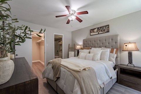 A bedroom with a large bed and a ceiling fan.