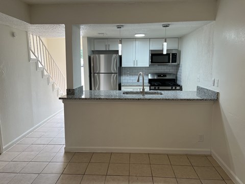 A kitchen with a refrigerator, microwave, and stove top oven.