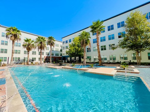 Resort style pool with palm trees and courtyard at Lofts on Main Apartments, San Antonio, Texas