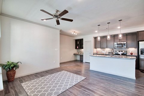 A modern kitchen with a fan on the ceiling and a dining area with a table and chairs.
