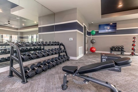 Weight training area with dumbbells and workout bench at Sienna at Westover Hills Apartments, San Antonio, 78253