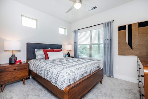 Modern bedroom with upholstered headboard and ceiling fan at Sienna at Westover Hills Apartments, San Antonio