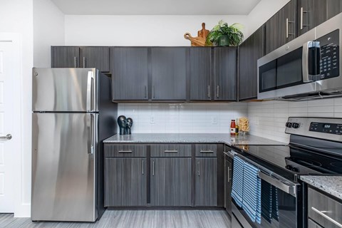 A modern kitchen with a stainless steel refrigerator and black cabinets.