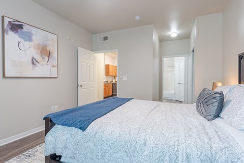 A bedroom with a large bed and a painting on the wall.