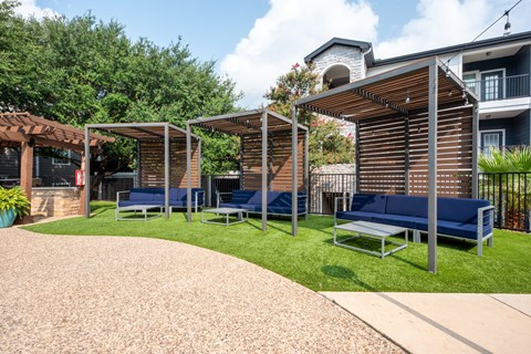 A patio area with a blue cushioned bench and a wooden pergola.