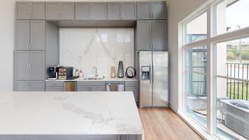 a kitchen with gray cabinets and a marble counter top at The Fitzroy San Marcos, Texas