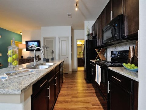 A kitchen with black cabinets and a granite countertop.