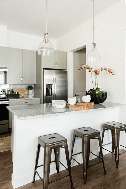 A kitchen with a white counter and three stools.