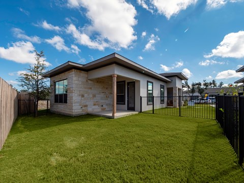 A modern house with a stone exterior and a black fence.