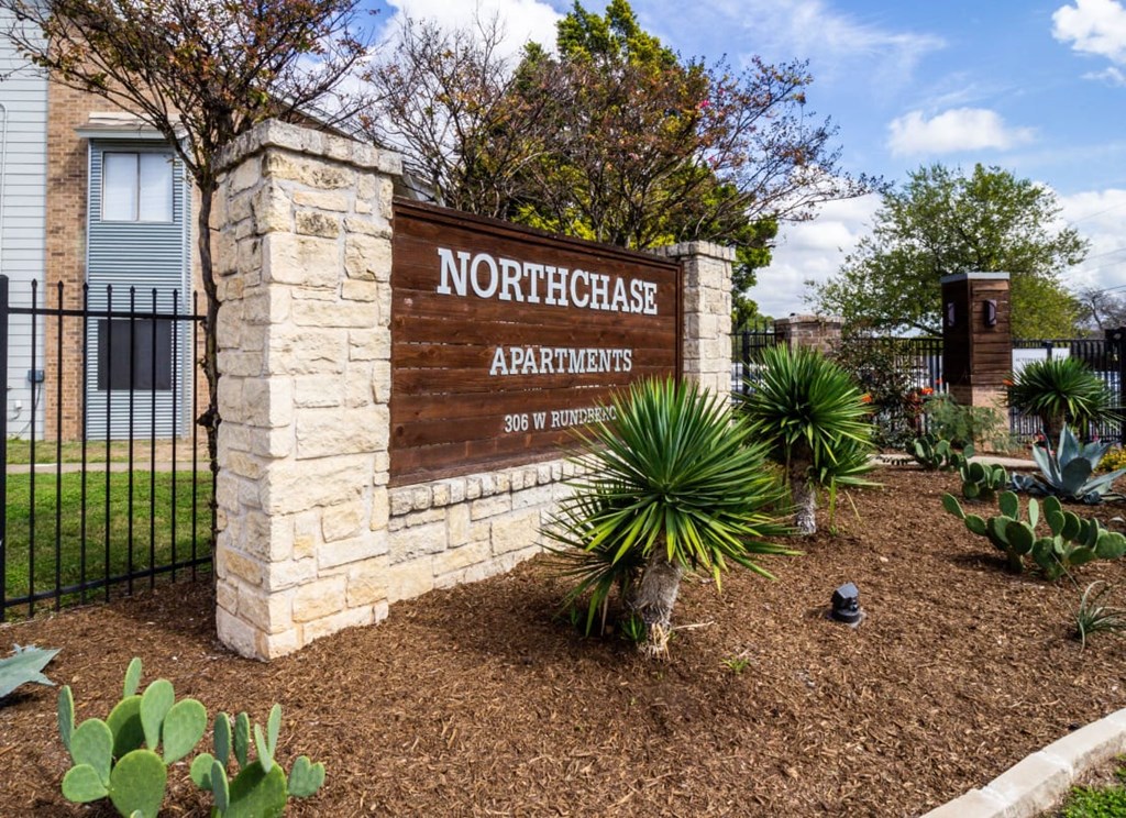 a sign apartments in front of a fence and plants at Northchase, Austin, TX, 78753